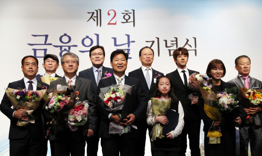 31일 서울 여의도 63빌딩에서 열린 제2회 금융의 날 기념식이 열렸다. 왼쪽부터 국민훈장을 받은 정재성 신용회복위원회 구미지부장(국민훈장), 안중원 시인·소설가 (국무총리표창), 장범식 숭실대 교수(국민훈장), 최종구 금융위원장, 이만수 전 SK 감독(국민포장), 최흥식 금융감독원장, 김나연 학생(금융위원장표창), 가수 황치열, 청년창업가 박예나 씨(대통령표창), 구두미화원 윤재천 씨(국무총리표창).  연합뉴스